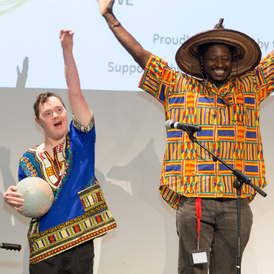Alex and Tichawona standing with arms raised on stage after a performance