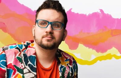A photo of Oliver wearing a colourful blazer and blue glasses is added onto a pink and yellow watercolour background