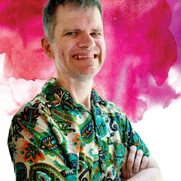 2024 Access Arts Achievement Award Winner - Michael Russell. Michael is facing the camera with his arms crossed. He is wearing a colourful Hawaiian shirt and he is smiling at the camera.